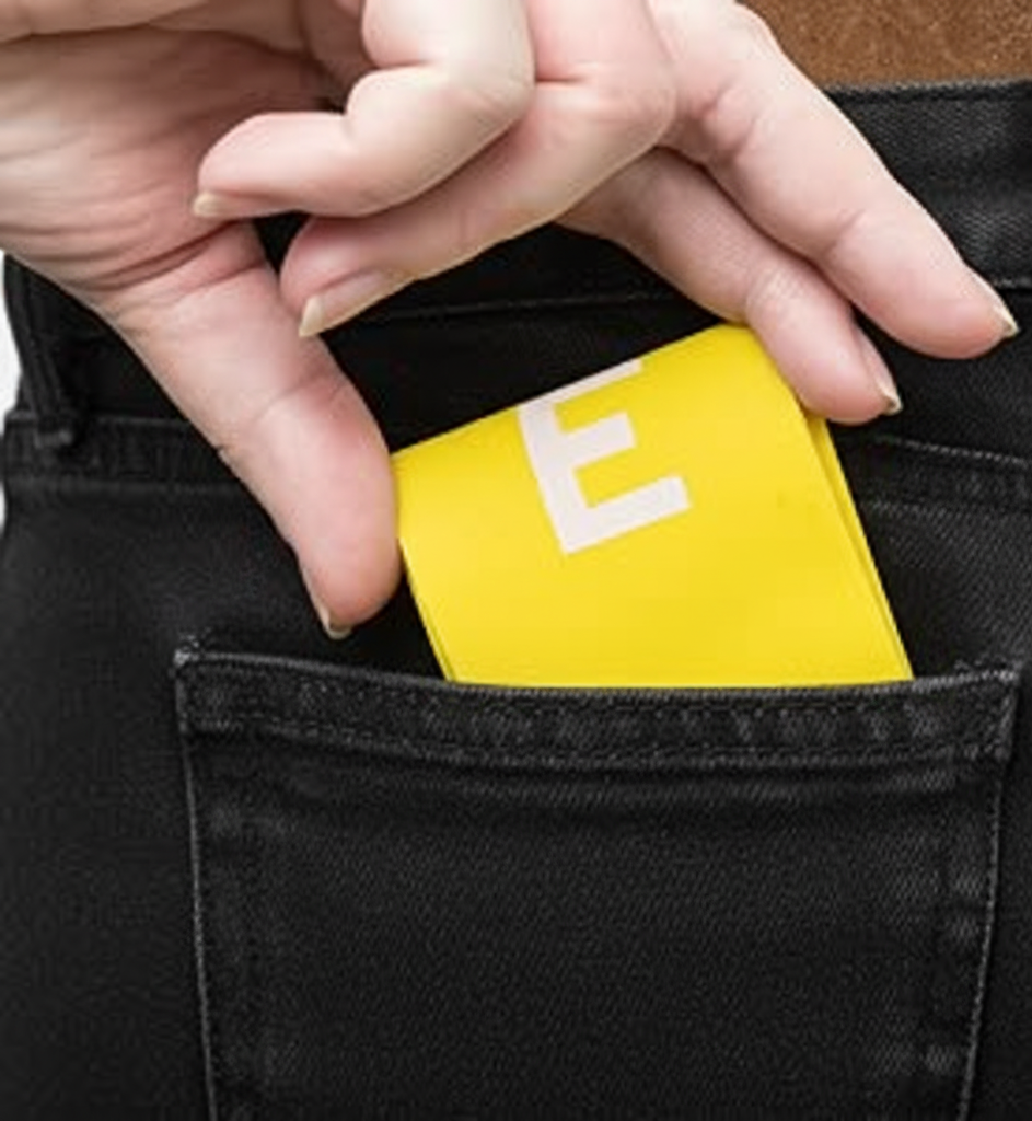 Hand placing a yellow resistance band with 'E' into a black pocket.